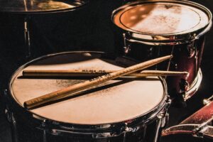 Photo by Matthijs Smit pair of brown wooden drumsticks on top of white and gray musical drum